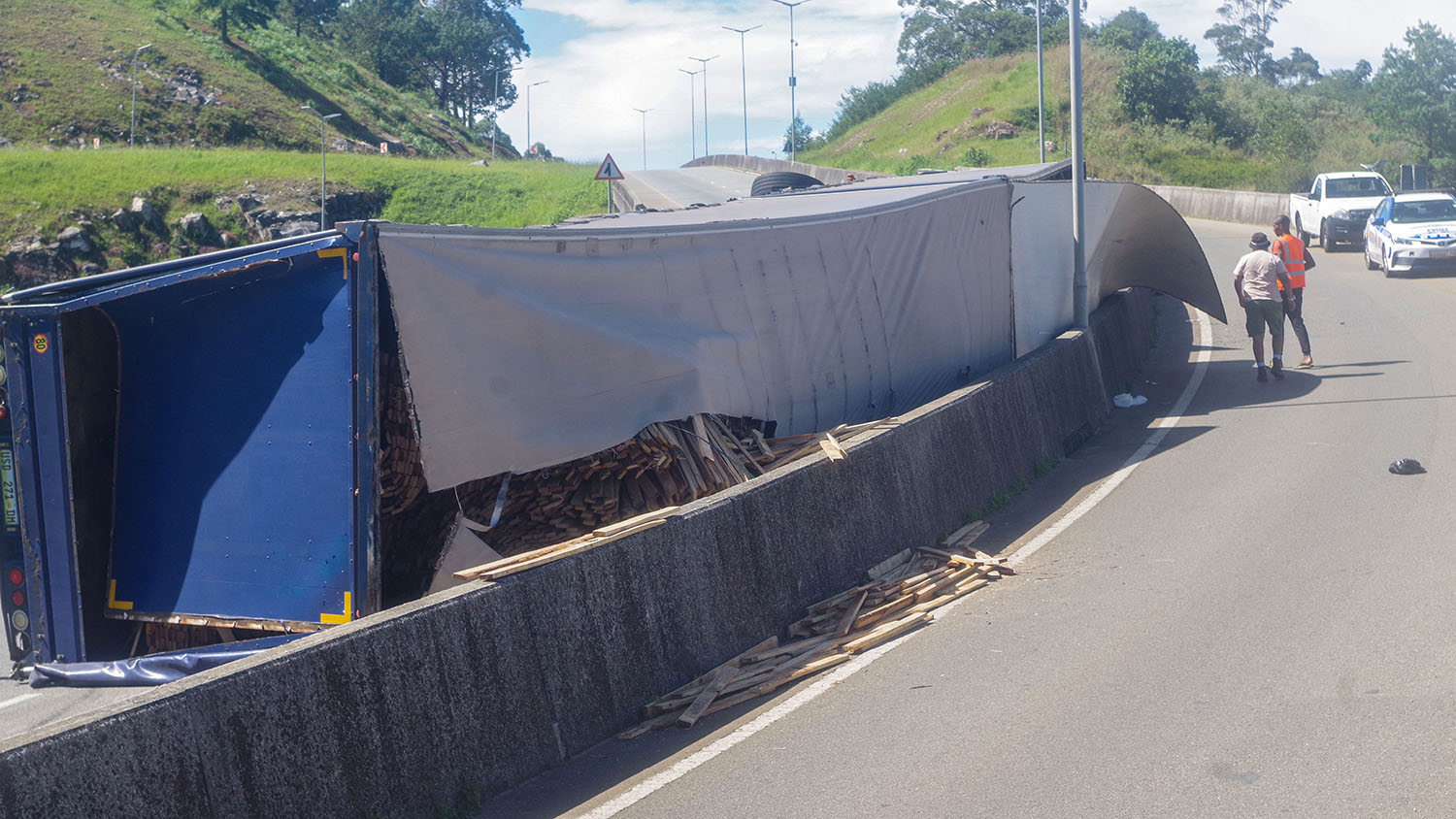 The load of planks leaning against the concrete median after the accident. 